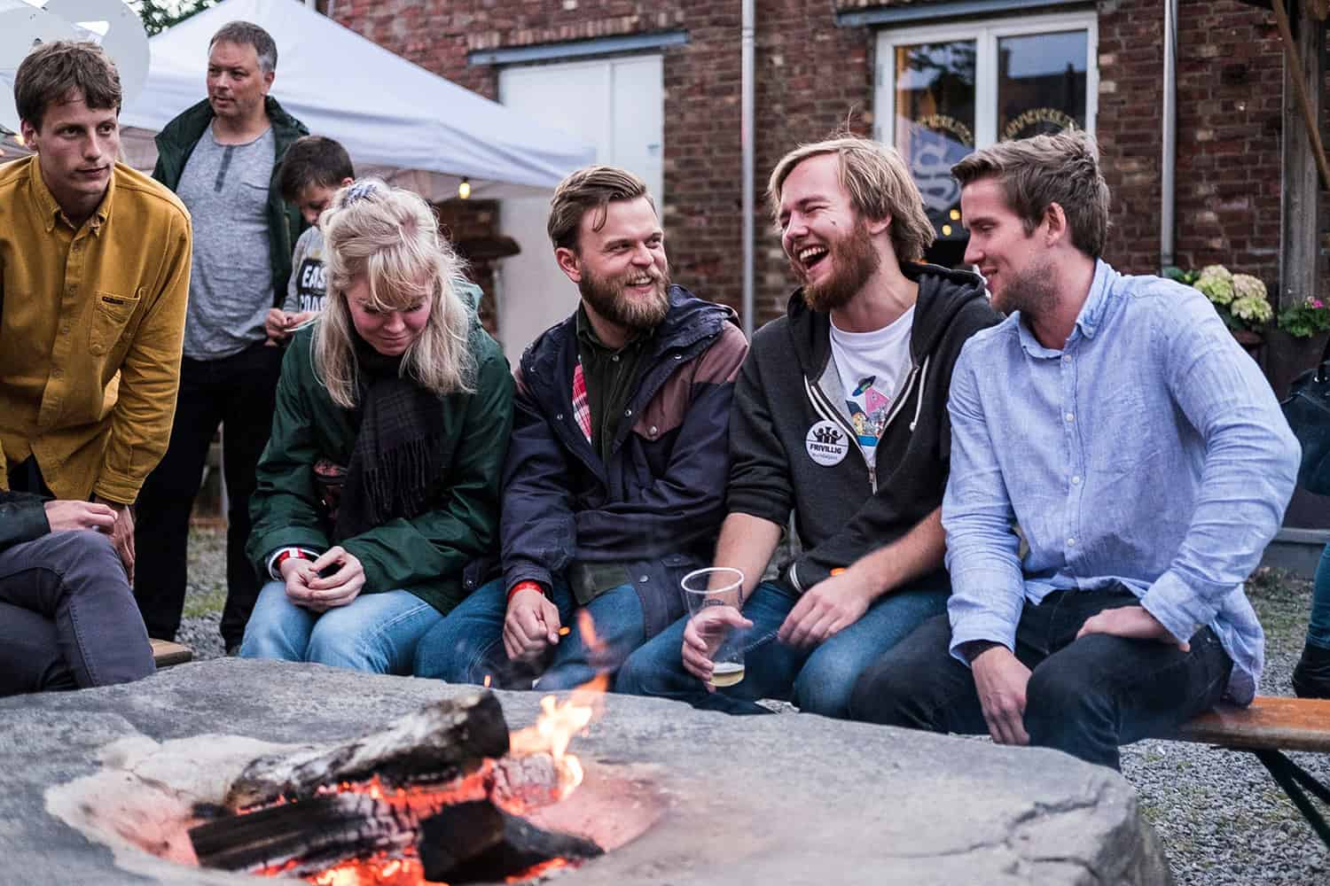Mennesker som ler og snakker rundt et bål utenfor Bueverket